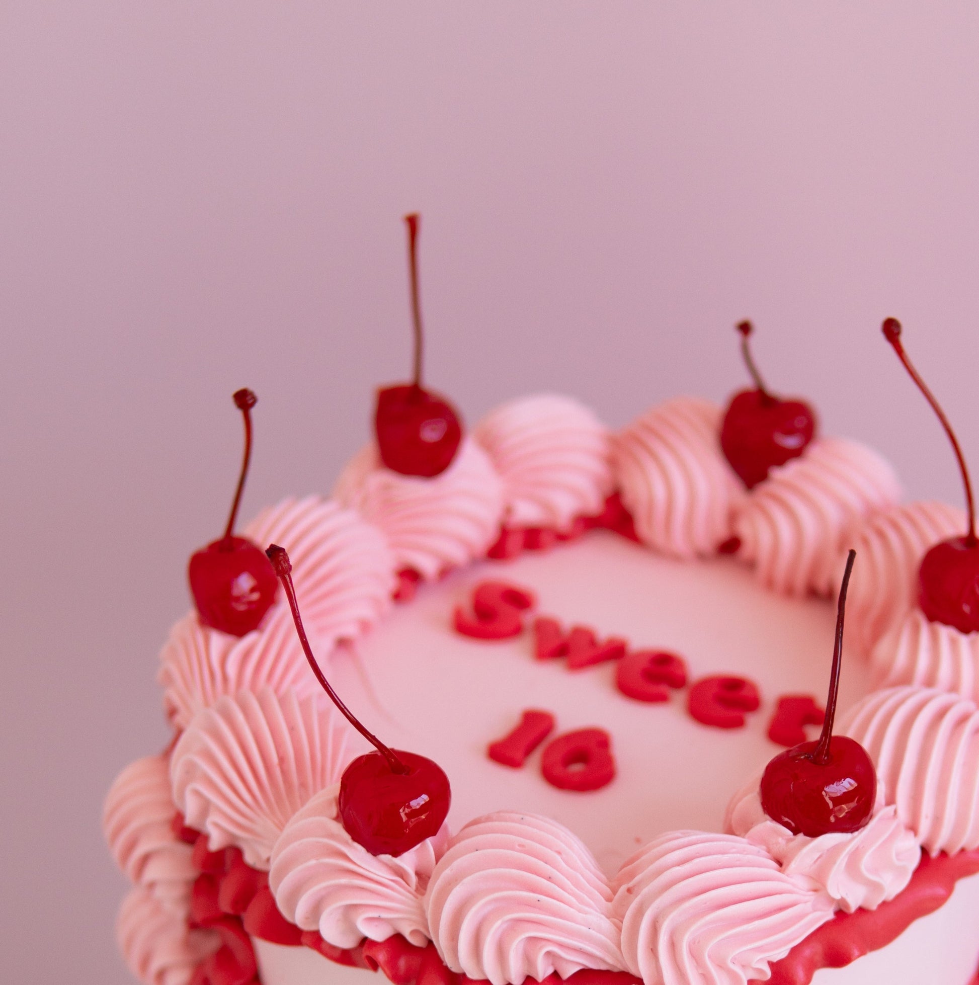 Red and pink Retro cake, with fun old school piping and juicy red cherries ontop